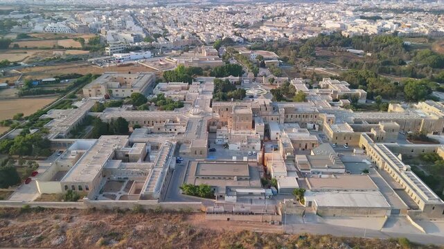 Attard, Malta, Mount Carmel Hospital psychiatric care complex with historic stone buildings and urban greenery in the Northern Region, Mediterranean architecture in aerial view.
