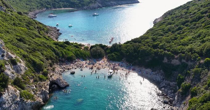 Aerial drone view of Porto Timoni double beach in Corfu, Greece. Turquoise Ionian sea, green cliffs, and boats in summer vacation paradise.