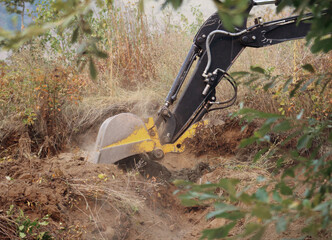 Excavator digging soil during land clearing and earthmoving © Nicola
