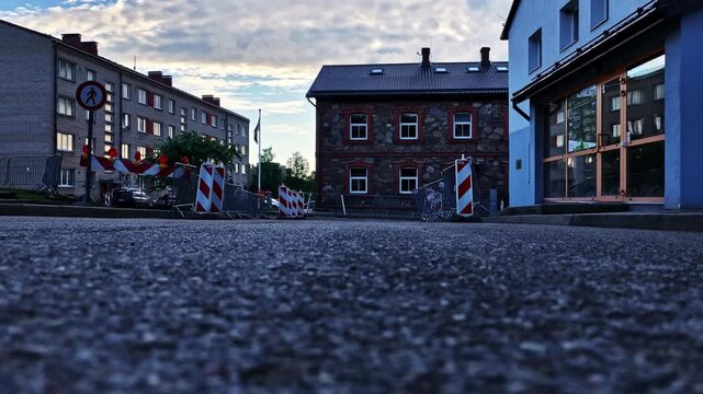 Empty town street with construction barriers blocking the road between residential buildings
