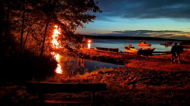 People celebrating Midsummer night with a bonfire on a lakeshore during twilight