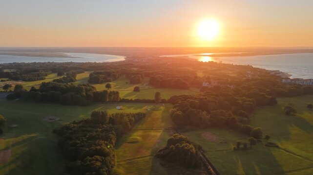 Vibrant sunset over Howth Peninsula with Dublin cityscape and green park aerial drone