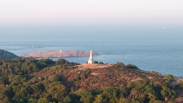 Golden hour drone over Killiney Hill and historic obelisk Dalkey Island backdrop, Dublin, Ireland
