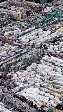 Tightly packed plastic rubbish bales form dense rows at a recycling yard, viewed from above in overcast daylight.