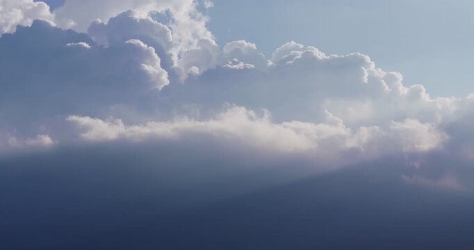 Time lapse of heavenly 3/4 backlit clouds in motion, with a blue sky background