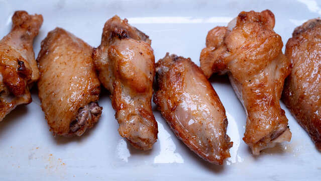 detailed view of crispy baked chicken wings with seasoned skin on white plate