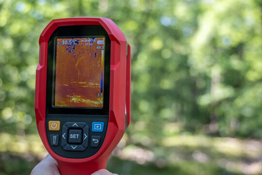 W&auml;rmebildkamera im Einsatz w&auml;hrend einer Waldwanderung. Die Hand h&auml;lt ein Thermografieger&auml;t, welches die W&auml;rmeverteilung der B&auml;ume und Natur auf einem Display visualisiert. Hochmoderne Technik.