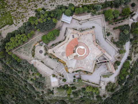 Aerial view of the star-shaped Fort de Salses with red tiled roofs surrounded by green vegetation.