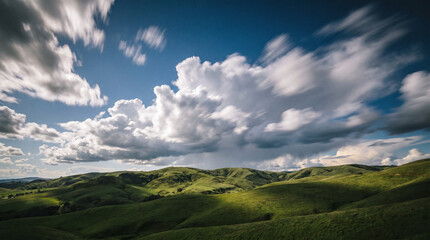 Fototapeta premium Vibrant Green Rolling Hills Under a Dramatic Moving Sky with Fluffy White Clouds and Deep Blue Atmosphere