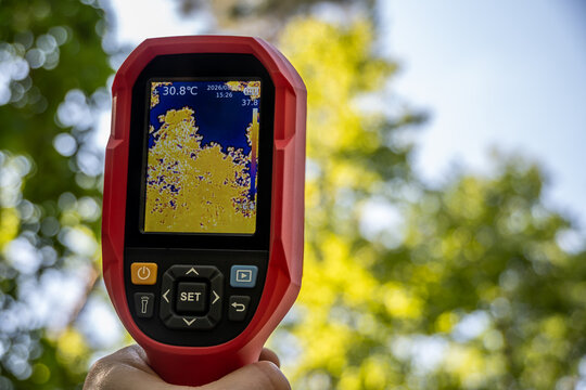 W&auml;rmebildkamera zeigt im Wald Temperaturunterschiede von Baumwipfeln und Himmel. Ein technisches Ger&auml;t misst Infrarotstrahlung in der Natur f&uuml;r &ouml;kologische Analysen und Forschung.