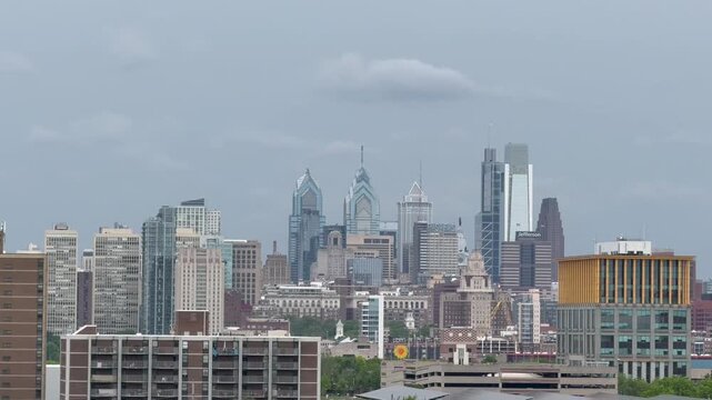 Tilt‑down aerial footage transitioning from the sky down to a clear view of the Philadelphia skyline. Establishing Shot