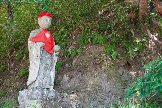 Traditional Jizo Stone Statue with Red Bib in a Forest at Mount Hiko, Fukuoka, Japan