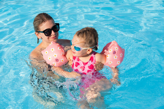 Happy Woman and Young Girl Having Fun in an Outdoor Swimming Pool