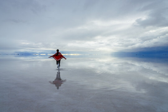 Traveller in a red poncho on the Salar de Uyuni, Bolivia