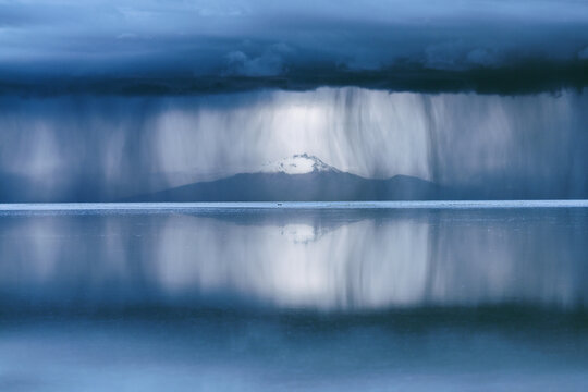 Rain and virga over a mountain at the Salar de Uyuni, Bolivia