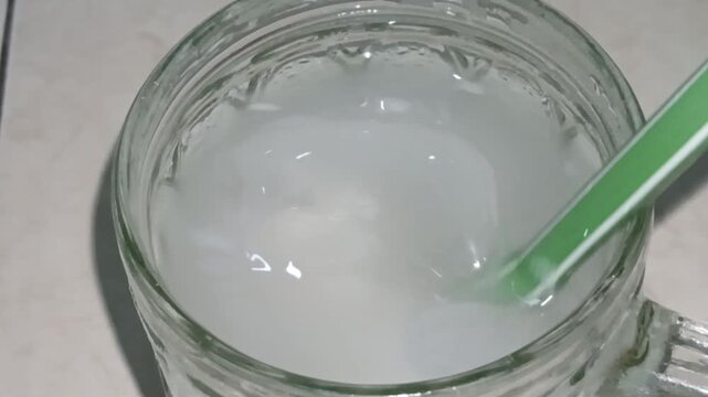 young coconut ice in a glass, stirred with a straw