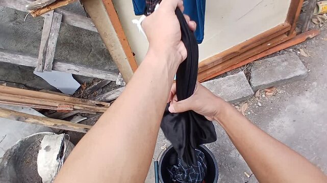 Someone is hanging up pants to dry by wringing them out with both hands
