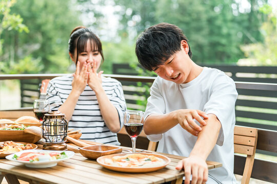 A couple is having trouble with insect bites while eating outdoors.