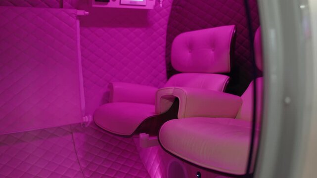 Modern hyperbaric oxygen therapy capsule interior with comfortable seats and relaxing pink lighting for wellness, rejuvenation, and health treatments in a contemporary spa or clinic setting