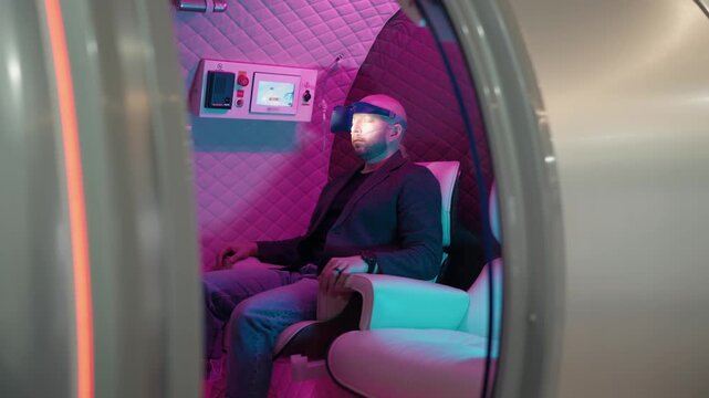 Man wearing a virtual reality headset relaxing inside a futuristic sensory deprivation chamber during a light therapy session. Modern technology for meditation, stress relief, and wellness