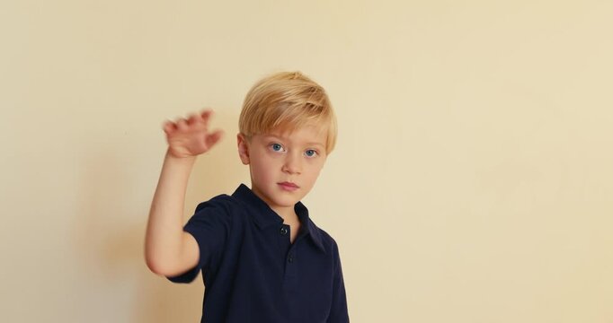 Adorable blond little boy waving goodbye hello