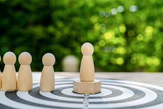 Wooden figure on a platform and dartboard a leadership concept representing the achievement of goals.