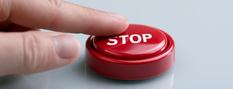 Finger pressing red Stop button on smooth grey surface  