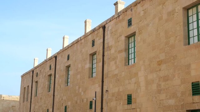 military barracks facade fort st elmo green shutter windows chimney stacks limestone wall low angle valletta malta coastal fortification historic architecture star fort military accommodation