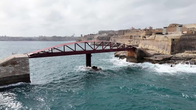 aerial pull back fort st elmo red breakwater bridge valletta malta overcast sky rough sea grand harbour marsamxett harbour coastal fortification drone reveal internationally recognized heritage site