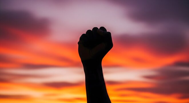 Human fist raised in protest against a vibrant dramatic sunset sky