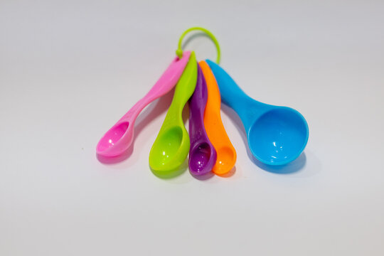 Set of five colorful plastic measuring spoons for cooking and baking on a white background
