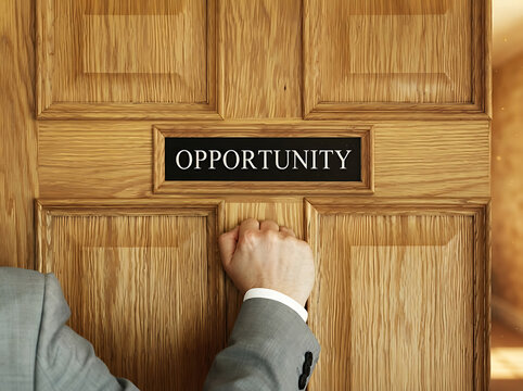 Hand knocking on a wooden door with an opportunity sign