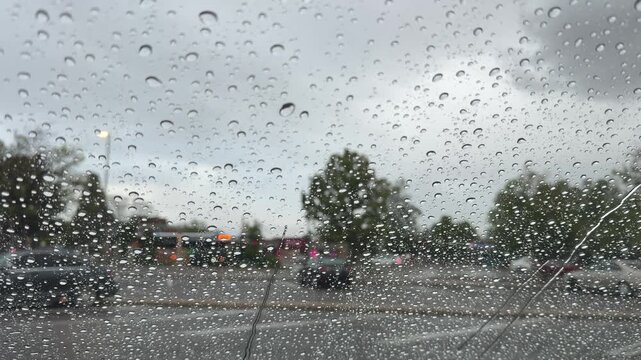 Raindrops falling on a car windshield
