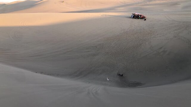 Person sandboarding down huge desert sand dune in ica, peru
