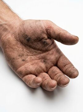 Close-up of a dirty, weathered hand with ingrained dirt and calluses.