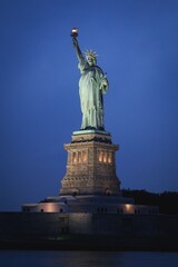 Statue of Liberty at Dusk in New York Harbor with Illuminated Torch © HAFIZ