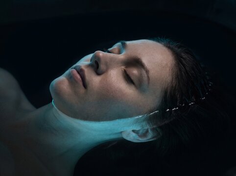 Close up profile of woman floating peacefully in dark water during sensory deprivation float therapy