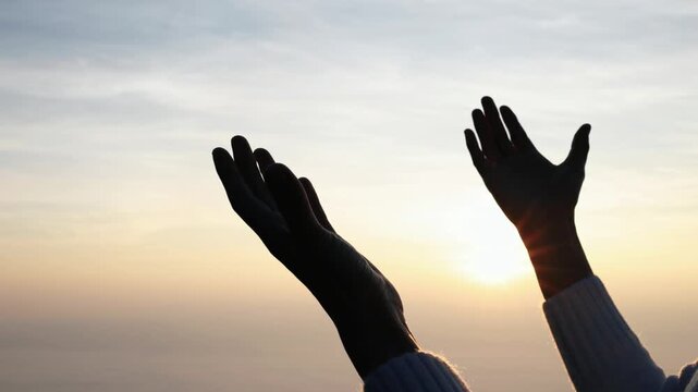 Moving footage captures silhouetted hands raising upwards, symbolizing prayer, worship, and spiritual connection