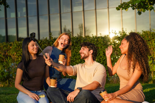 University classmates making a video call during a coffee break outdoors on campus, sharing happy moments
