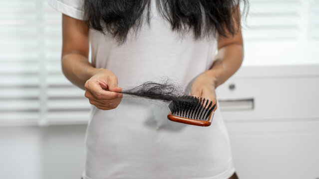 Woman holding a comb full of shed hair, showing hair loss and daily grooming at home