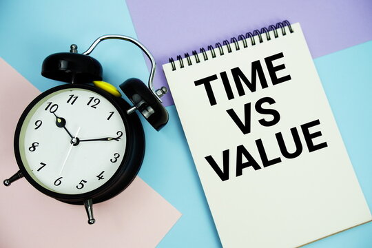 Time vs Value text written on notepad with alarm clock flat lay on multicolor pastel background