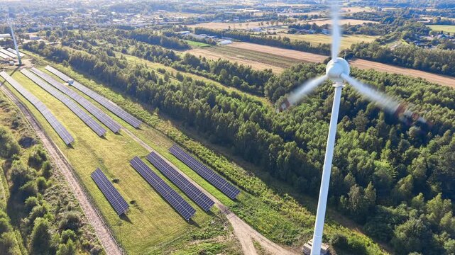 Wind turbine standing next to solar panel rows