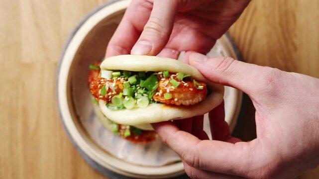 Hands hold shrimp bao close, showing shrimp coated in spicy sauce. Shrimp bao filling combines shrimp, cucumber, scallion and chilli. Pack shrimp bao with rice, Asian salad or noodles for lunch box.