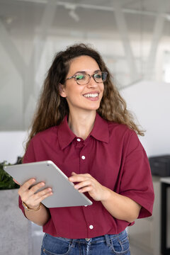 Portrait of smiling businesswoman using digital tablet for reviewing business data, checking work emails, managing workflow through professional application, communicating online in corporate office