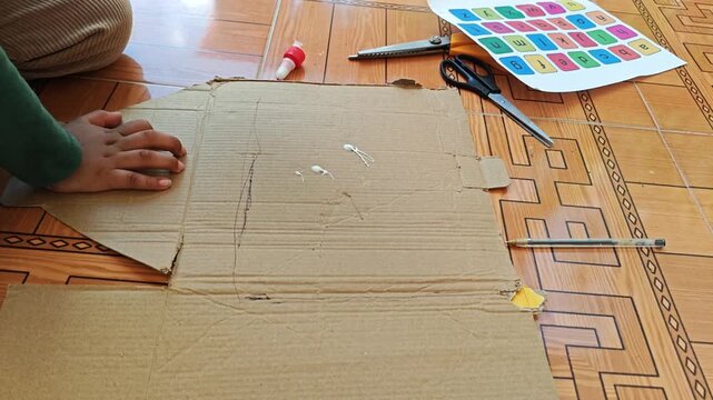 Dripping liquid white glue onto recycled cardboard surface for educational craft project