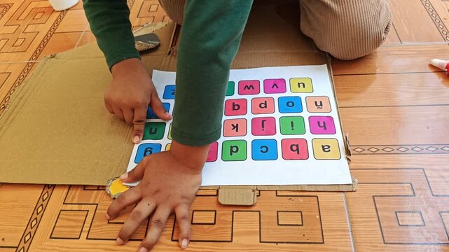 Child smoothing and pressing paper sheet edges onto cardboard surface