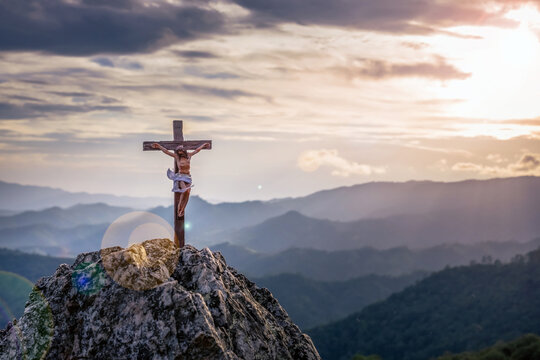 Silhouettes of god crucifix symbol on top mountain with bright sunbeam on the colorful sky background