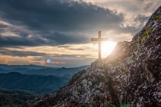 Silhouettes of crucifix symbol on top mountain with bright sunbeam on the colorful sky background