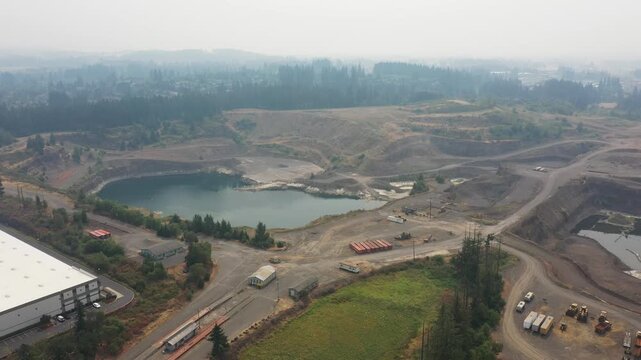 4K aerial drone footage of an active aggregate quarry in Sherwood, Oregon, USA under heavy wildfire smoke and hazy skies. Large open pit mine extracting rock and gravel amid poor air quality condition