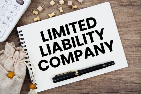 Limited Liability Company text written on notepad with pen and calculator on wooden background